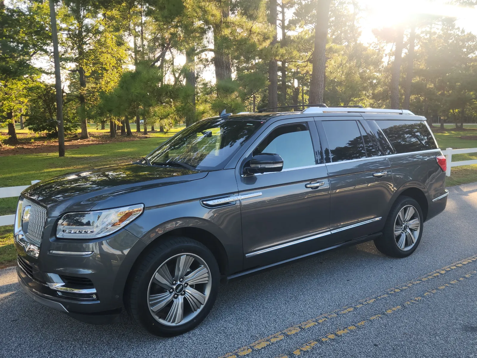 Dark gray Lincoln Navigator L on a tree-lined coastal road at golden hour, Icon Transportation Wilmington NC private SUV service